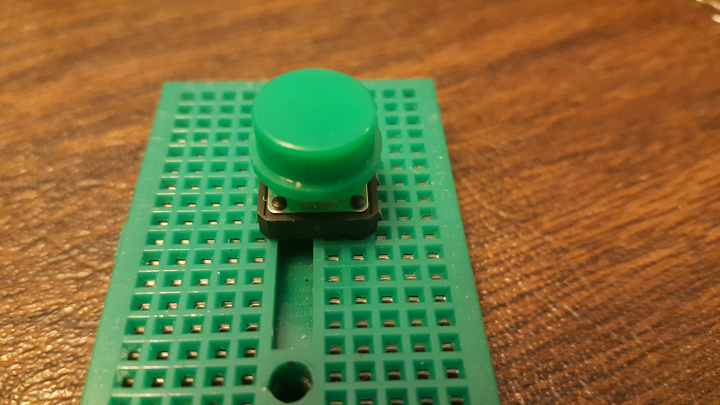 Side view of button being inserted into mini breadboard
